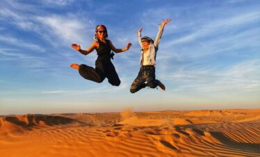 Two people playing on sand dunes Salalah Desert Safari