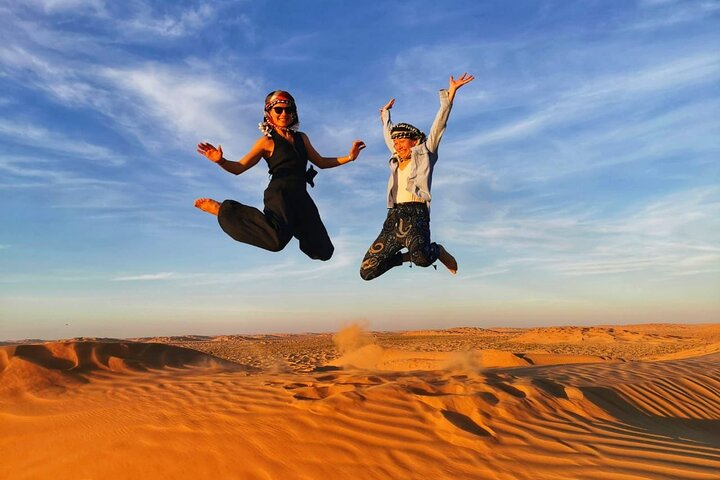 Two people playing on sand dunes Salalah Desert Safari