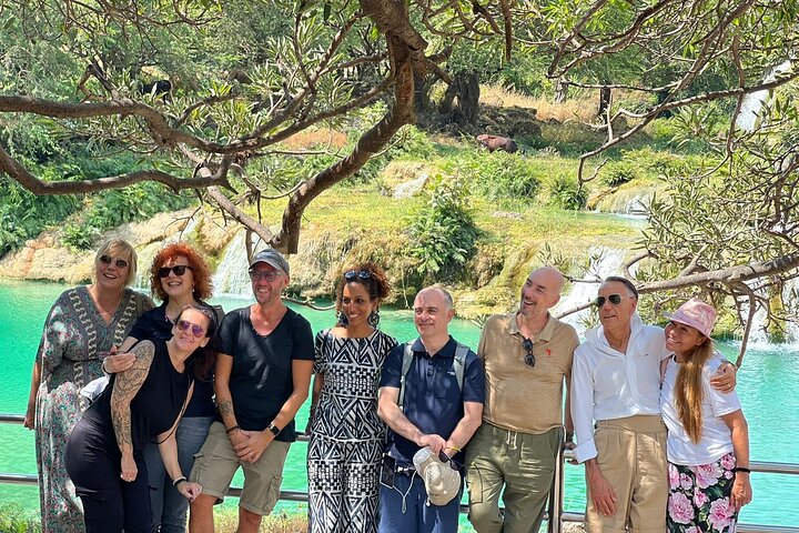Group of people in the background with Wadi Darbat waterfall in winter