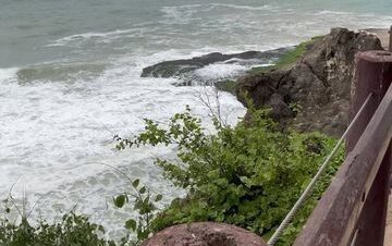 Mughsail Beach with turquoise water and rocky cliffs in the background