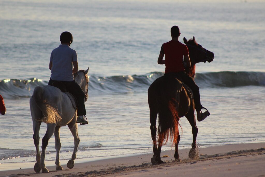 Horse riding along Salalah beach at sunset