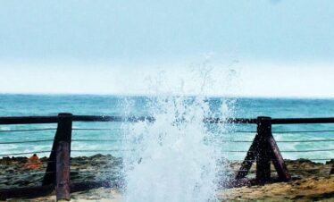 Waves crashing into natural blowholes at Mughsail Beach, Salalah