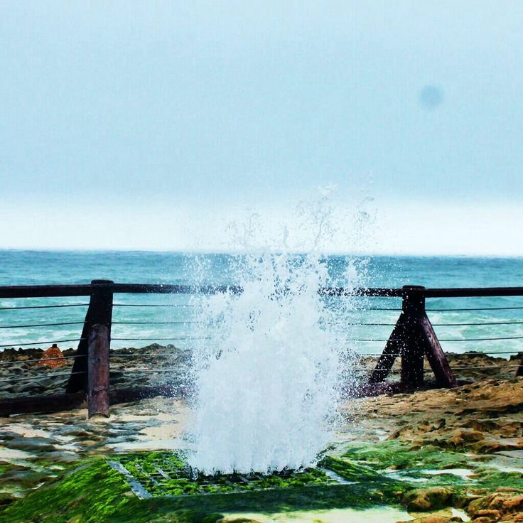 Waves crashing into natural blowholes at Mughsail Beach, Salalah