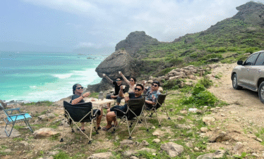 Group of people enjoying the sunset view from a cliff at Mughsail Beach